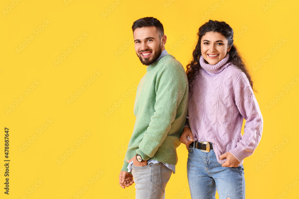 Obraz premium Happy young couple in warm sweaters on color background