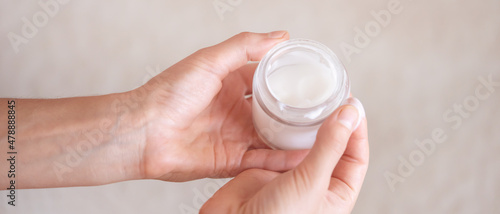 Female hands hold a jar of moisturizing cream.