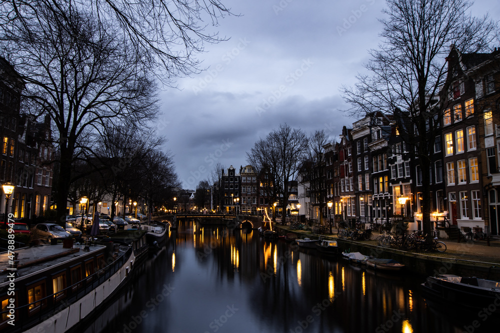 Amsterdam at night with canal and buildings. Lights in winter