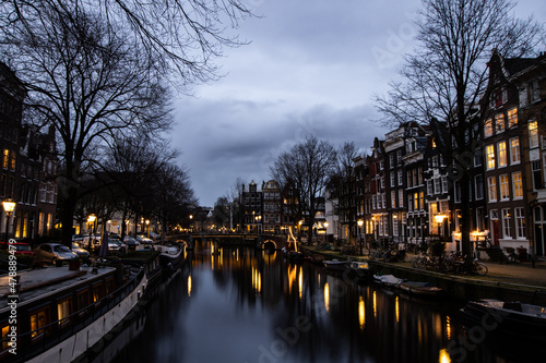 Amsterdam at night with canal and buildings. Lights in winter