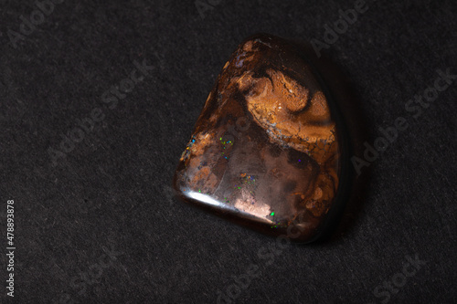 Colorful boulder opal gem from Koroit Australia on black background photo