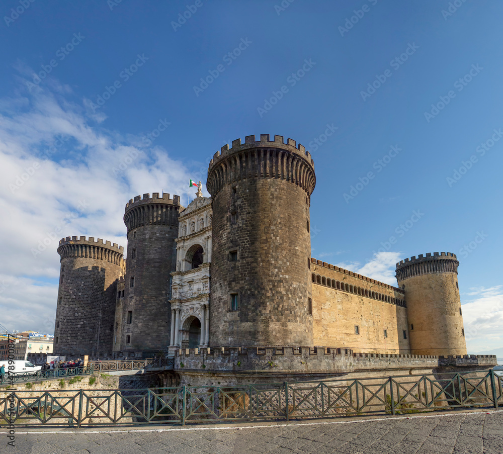 Wide view of the New Castle (Castel Nuovo) in Naples, Italy, in the sunny winter day, with white clouds in the blue sky