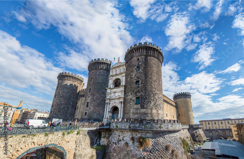 Wide view of the New Castle (Castel Nuovo) in Naples, Italy, in the sunny winter day, with white clouds in the blue sky