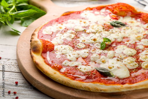 Italian pizza Margherita with tomato sauce and basil on white wooden table close up