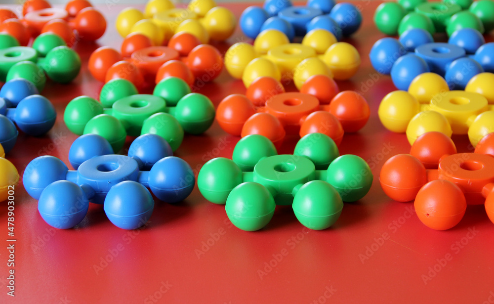 Pieces of plastic rainbow multicolored buildable toy blocks formed and arranged on red background Pieces of plastic rainbow multicolored buildable toy blocks formed and arranged on red background