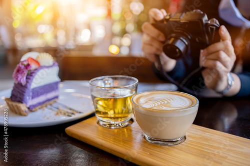 Woman using digital camera for take photo of cake and coffee in the cafe. Relax and recreation alone on holiday. photo