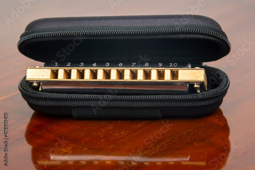 Harmonica in a case on a wooden background. Classical musical wind instrument.
