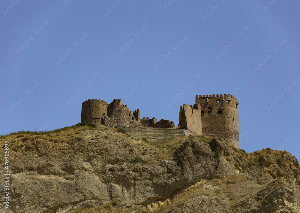 Ksani fortress, also known as the Mtkvari fortress in eastern Georgia, perched on a mount at the confluence of Ksani and Kura rivers. Brown brick and stone ancient walls, blue sky, stone cliff