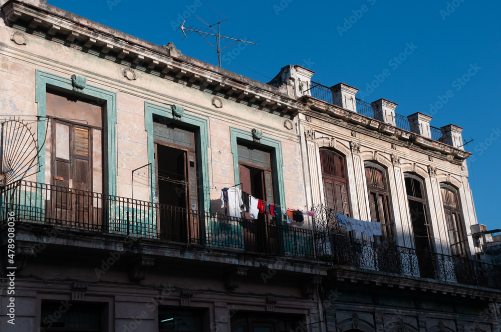 Clothes hanging on a balcony of a deteriorated classic-style facade on a street in Havana. Havana. Cuba