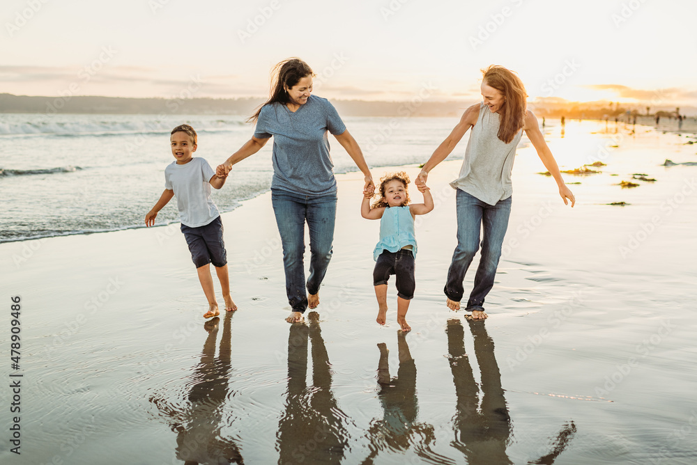 Two moms and kids running on wet sand Two moms and kids running on wet sand