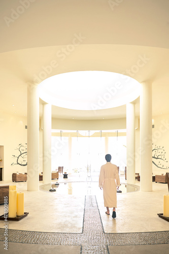 Man on vacation walking in robe in lobby of spa hotel