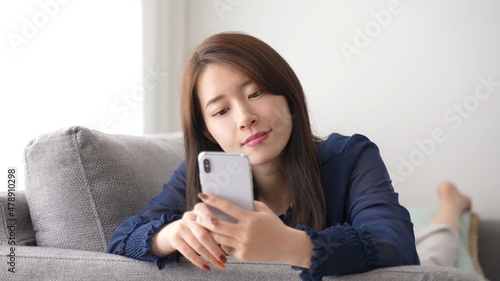 ソファでスマートフォンを使う女性