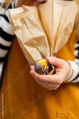 Close-up of woman holding bag with roasted chestnut