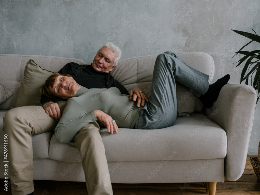 Senior couple resting on the couch having fun Senior couple resting on the couch having fun