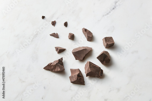 Broken pieces of dark chocolate on background