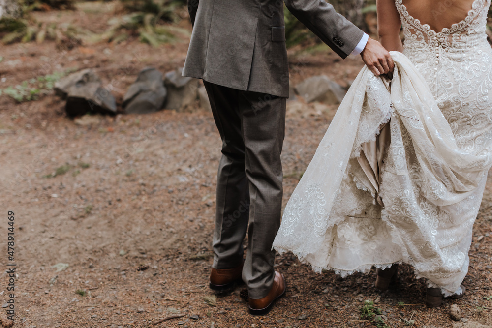 Groom Helping Bride Carry Dress on Trail Groom Helping Bride Carry Dress on Trail