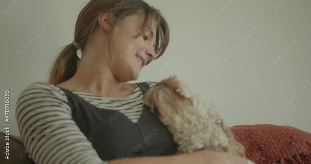 Young Pregnant Woman Cuddling Dog on Sofa at Home Young Pregnant Woman Cuddling Dog on Sofa at Home