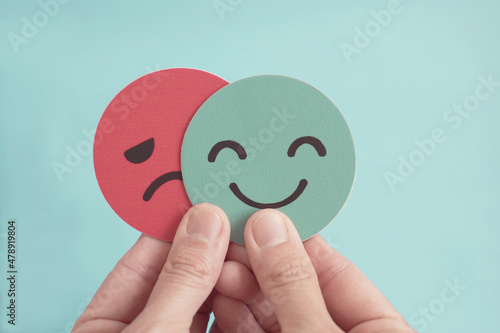 Fotografie Hands holding sad face hiding behind happy face, bipolar and anxiety, depression