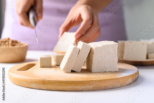 Papier peint Hand holding knife and cutting organic tofu on wooden board prepare for cooking,