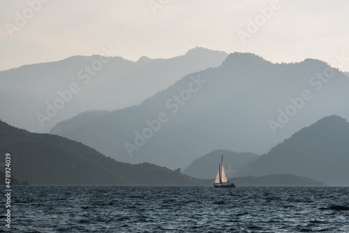 rolling mountains and a sailboat cruising photo