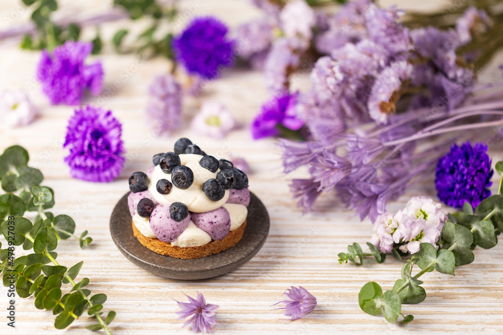 Blueberry Graham Cheesecake topped with fresh berries on white drift wood vintage table over a dry flowers and twigs background. Blueberry Graham Cheesecake topped with fresh berries on white drift wood vintage table over a dry flowers and twigs background.
