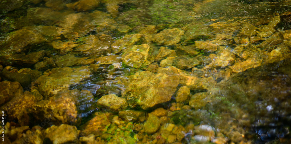 Water stream close-up view from above, Natural light passes through water surface to hit underwater ground gravel and stones. Water stream close-up view from above, Natural light passes through water surface to hit underwater ground gravel and stones.