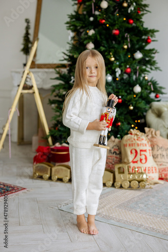 A girl with a nutcracker toy near Christmas tree photo