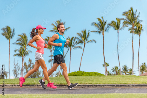 Sport fitness runners couple running lifestyle. Healthy people jogging together in summer city park outdoor, athletes training cardio on sidewalk.