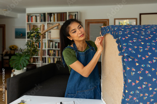 Asian woman upholstering a chair at home
