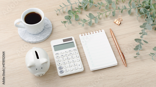 Calculator with piggy bank and notebook on light wood desk