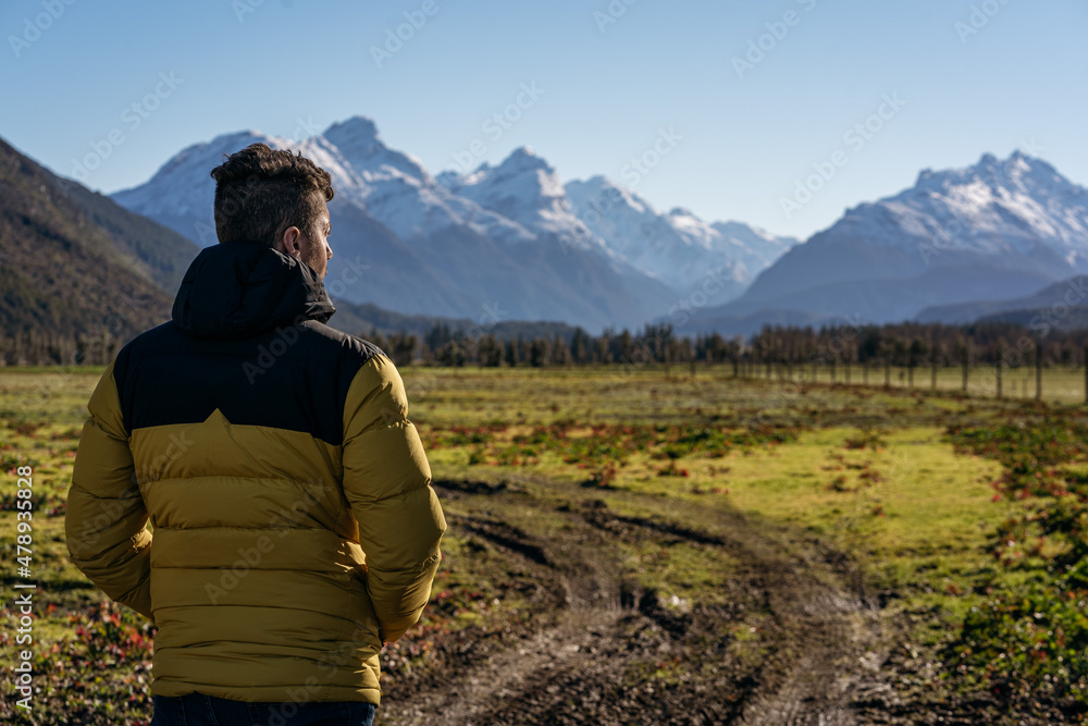 Man looking at the scenery of high mountains in a countryside. Glenorchy, New Zealand