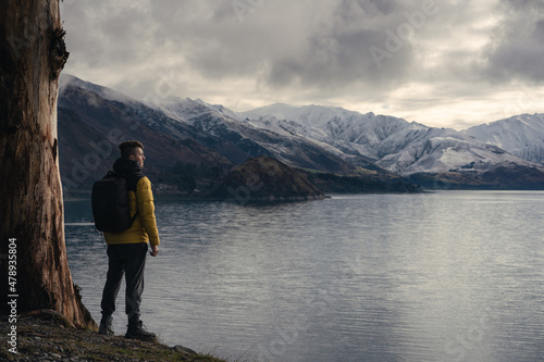 Man standing by a tree in Lake Hawea during winter.