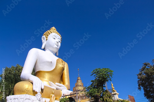 Huge sitting buddha image on bright blue sky view background at  phra that doi khum  temple in Chiang Mai of Thailand photo