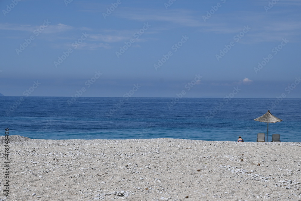 Fototapeta premium Strand mit Meer und Sonnenschirm an der Küste in Albanien, mit blauem Himmel 