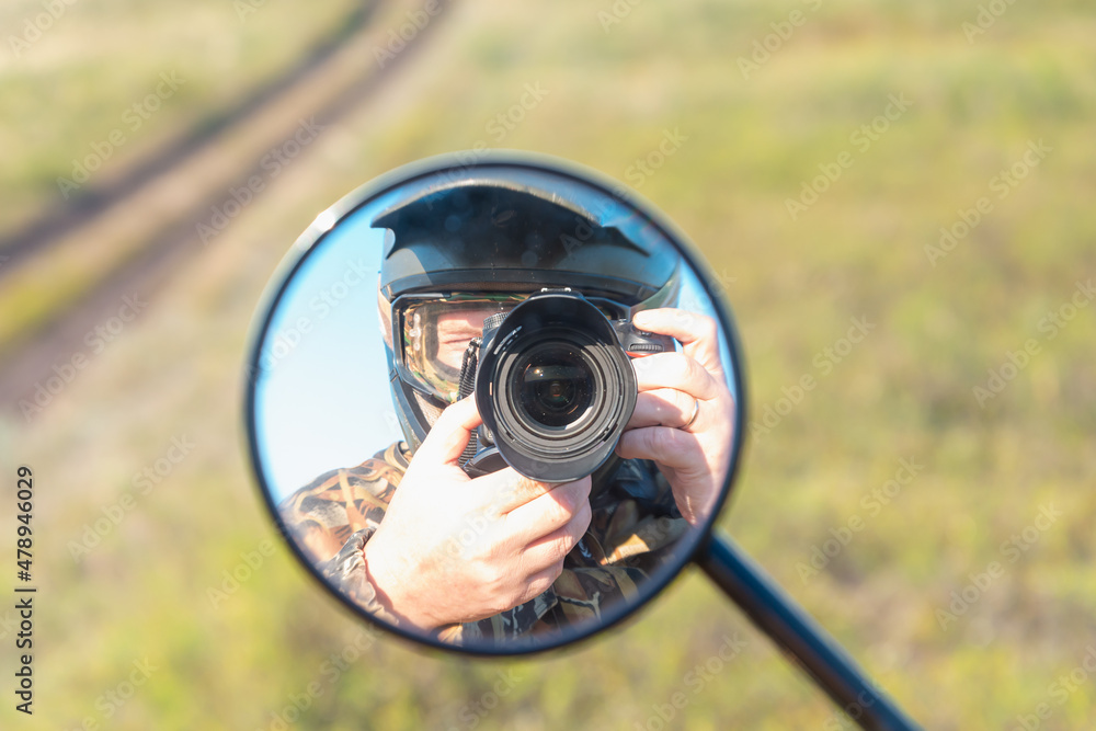 Motorcyclist with a camera in a helmet. Reflection in the mirror of a motorcycle. Motorcycle travel. Motorcyclist with a camera in a helmet. Reflection in the mirror of a motorcycle. Motorcycle travel.