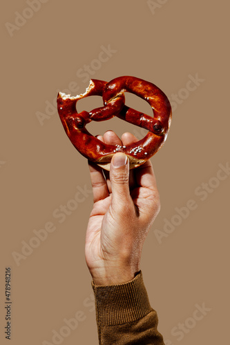 man has a nibbled pretzel in his hand photo