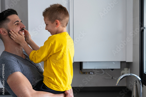 father with child in arms looking at each other smiling