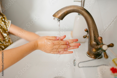 Kid's hands under tap water photo