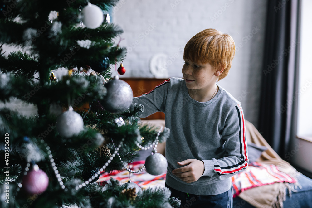 Boy feeling happy while decorating conifer tree at home Boy feeling happy while decorating conifer tree at home