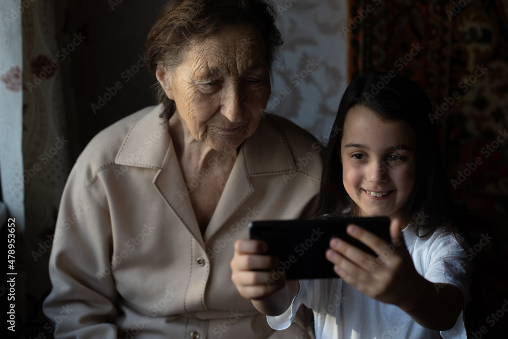 very old great-grandmother and granddaughter with a smartphone online very old great-grandmother and granddaughter with a smartphone online