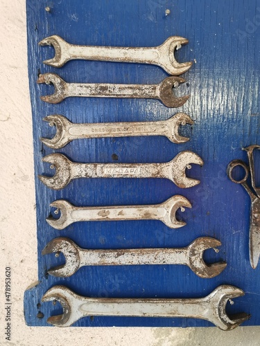 Variety of wrenches in a workshop on a blue background, Mechanic instruments on a wall, Maintenance tools, Steel repair tools, Supplies for home improvement and fixes photo