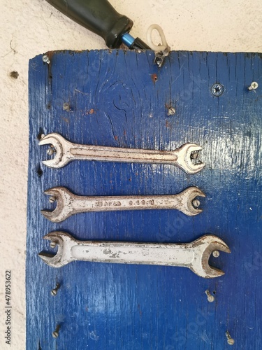 Variety of wrenches in a workshop on a blue background, Mechanic instruments on a wall, Maintenance tools, Steel repair tools, Supplies for home improvement and fixes photo