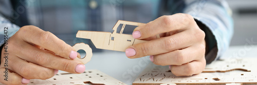 Tablou pe pânză Female hands assemble wooden toy car from different parts