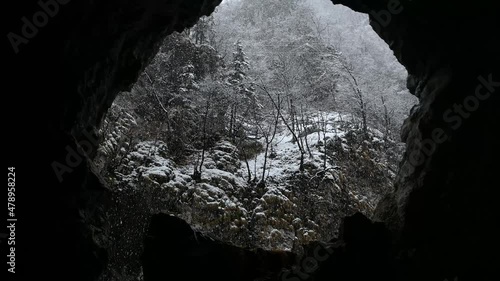Snow falling on a steep mountain range in Slovenia. Cold winter season in the Alps. Tranquil scenery, view from a hole or a cave. White snowflakes falling. Looking up, real time, static shot