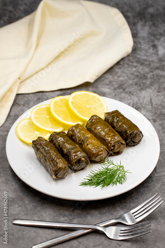 Stuffed grape leaves with olive oil on a dark background. Traditional Turkish cuisine delicacies. Delicious dolma (yaprak sarma). Vertical view. Close up photo
