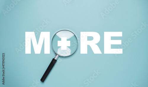 Magnifier glass with more wording and plus sign for value added , positive thinking and personal development concept.