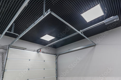 Garage with light walls, dark ceiling and automatic gates.