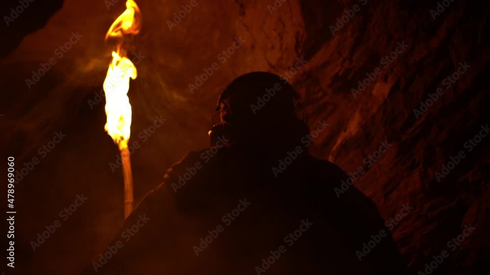 Man being trapped in a dark cave at night with a burning flickering torch