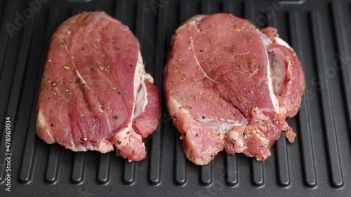 Pork is fried in a grill pan. Two pieces of pork are fried close-up