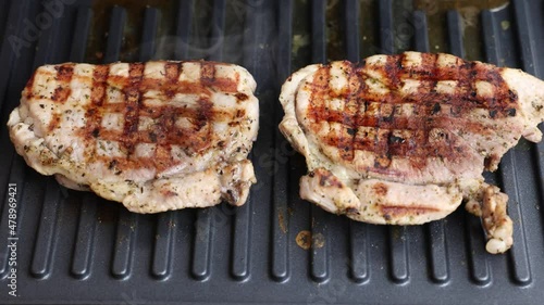 Pork is fried in a grill pan. Two pieces of pork are fried close-up